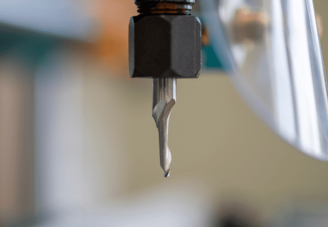 Detailed view of a solid router bit mounted in a CNC spindle, highlighting the sharp cutting flutes and tool geometry used for precision aluminium routing.