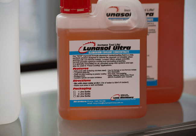 Close-up of a bottle of Lunasol Ultra aluminium coolant concentrate, showing product label with mixing directions, features, and contact details for reorders.